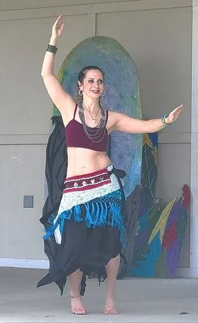 Jillian Ricks dancing in a belly dance costume with her arms raised