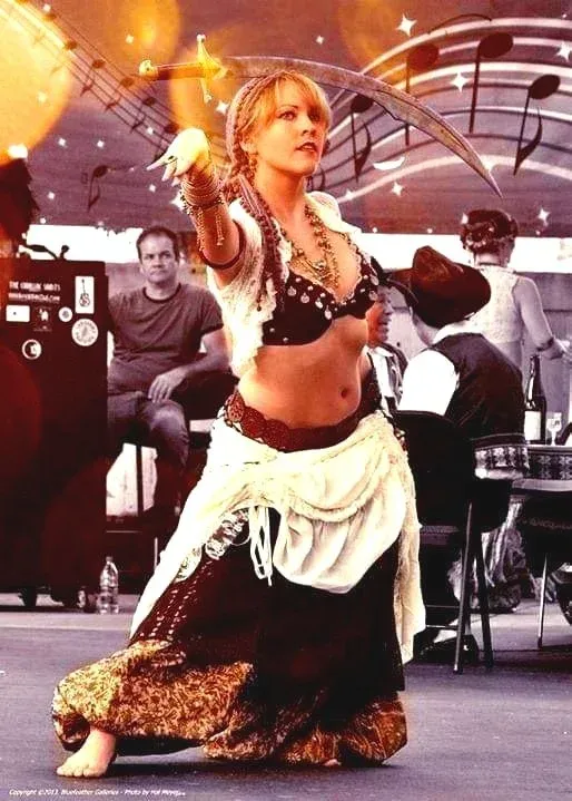 Suzie Rambo performing belly dance on stage, balancing a sword