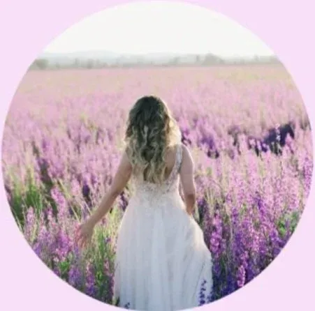 A woman in a white dress walking through a field of lavender