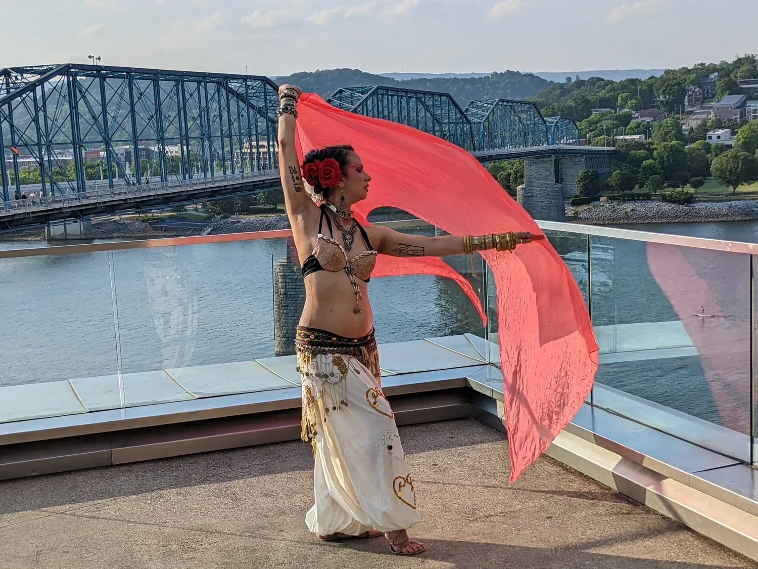 Crystal Lugo dancing with a red veil beside the river and a blue bridge