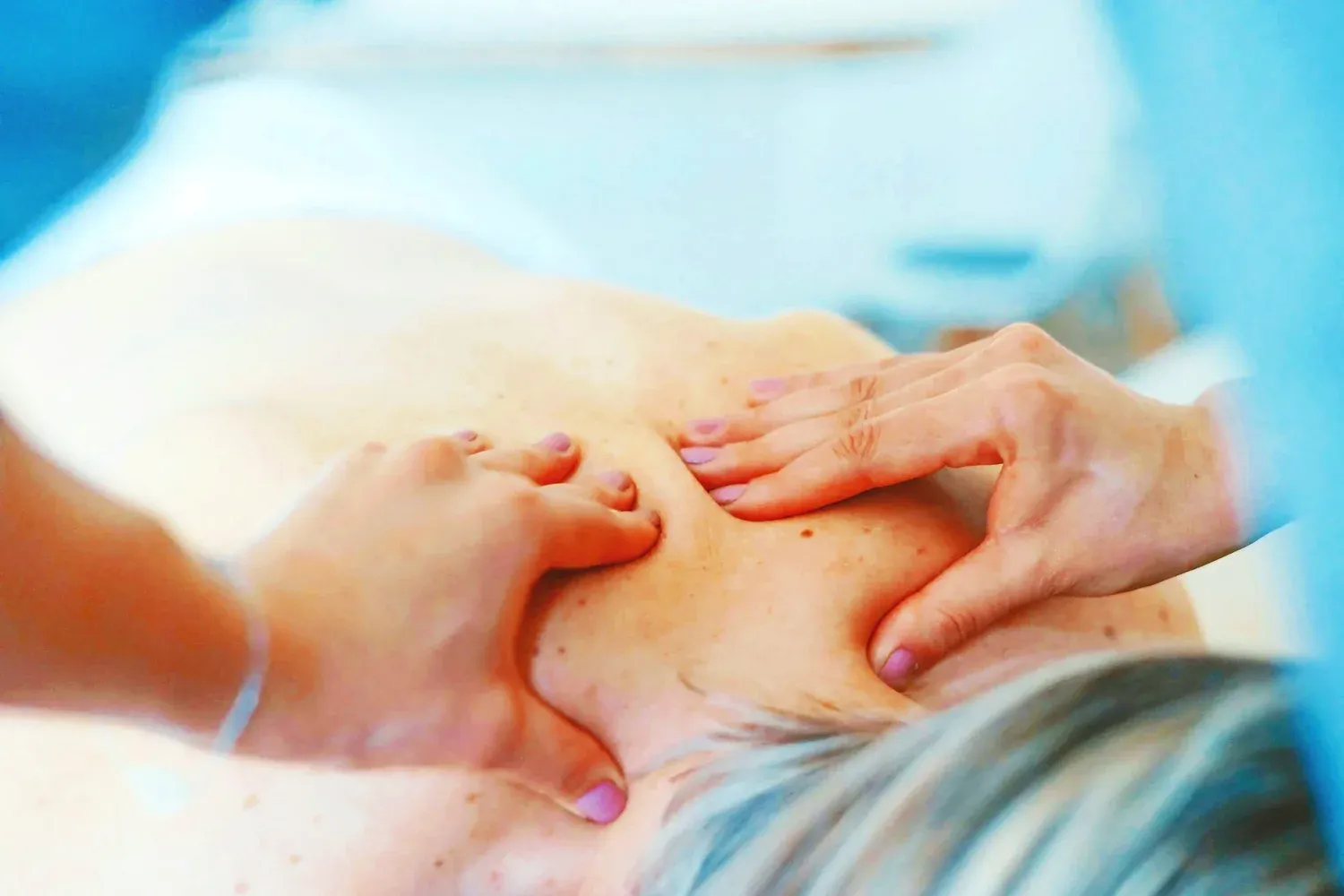 A massage therapist’s hands pressing into a client’s back